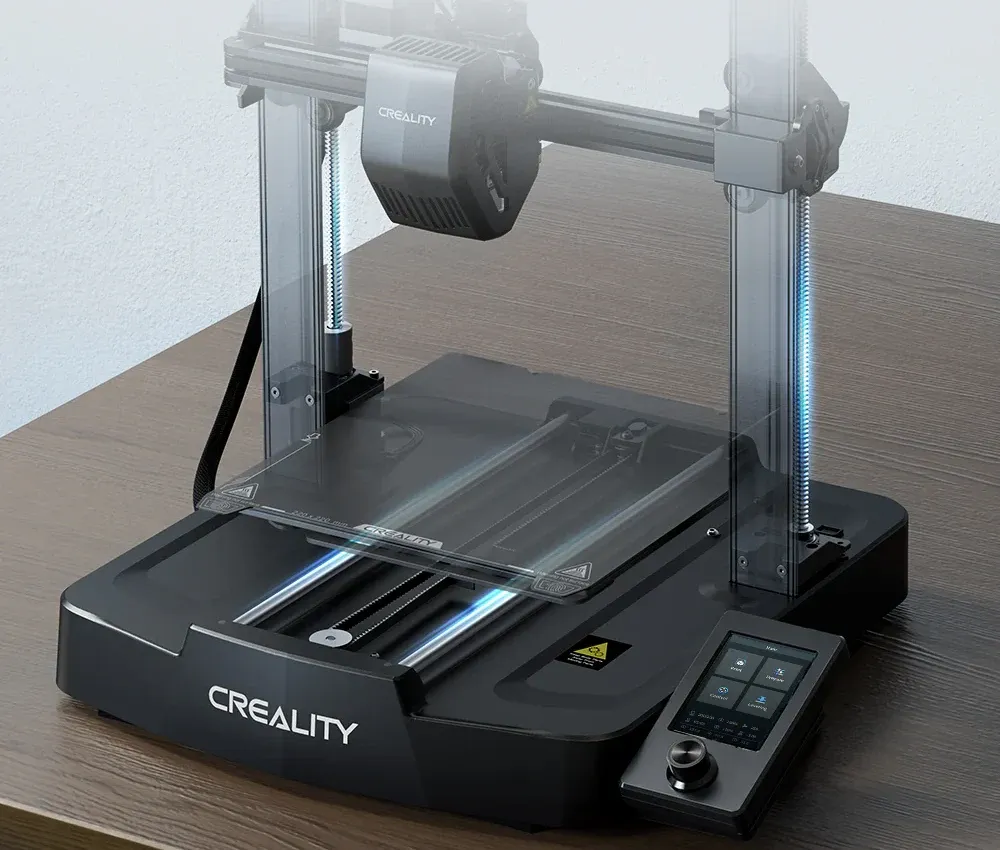 Impressora 3D Creality Ender 3 V3 SE sobre uma escrivaninha, mostrando as duas barras roscadas do eixo Z, a mesa de 220 mm e a tela com botão giratório